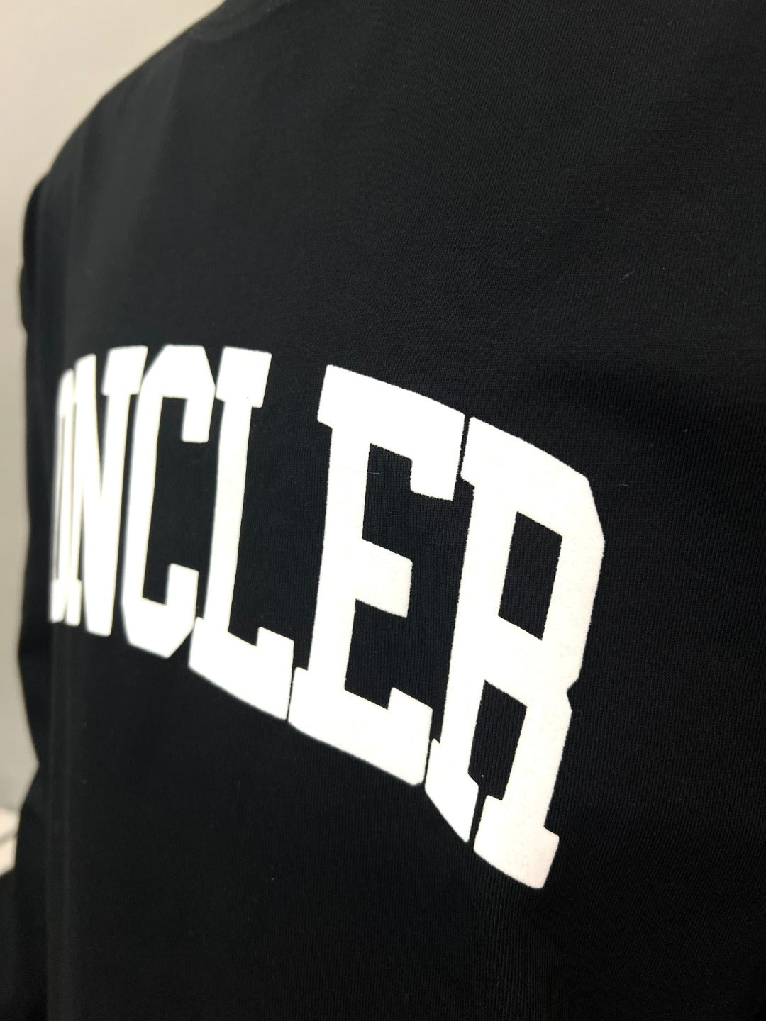 Black Moncler long-sleeve T-shirt side close-up of large white MONCLER logo