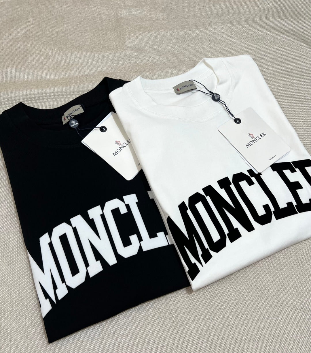 Two Moncler long-sleeve T-shirts, black and white, with oversized white MONCLER logo