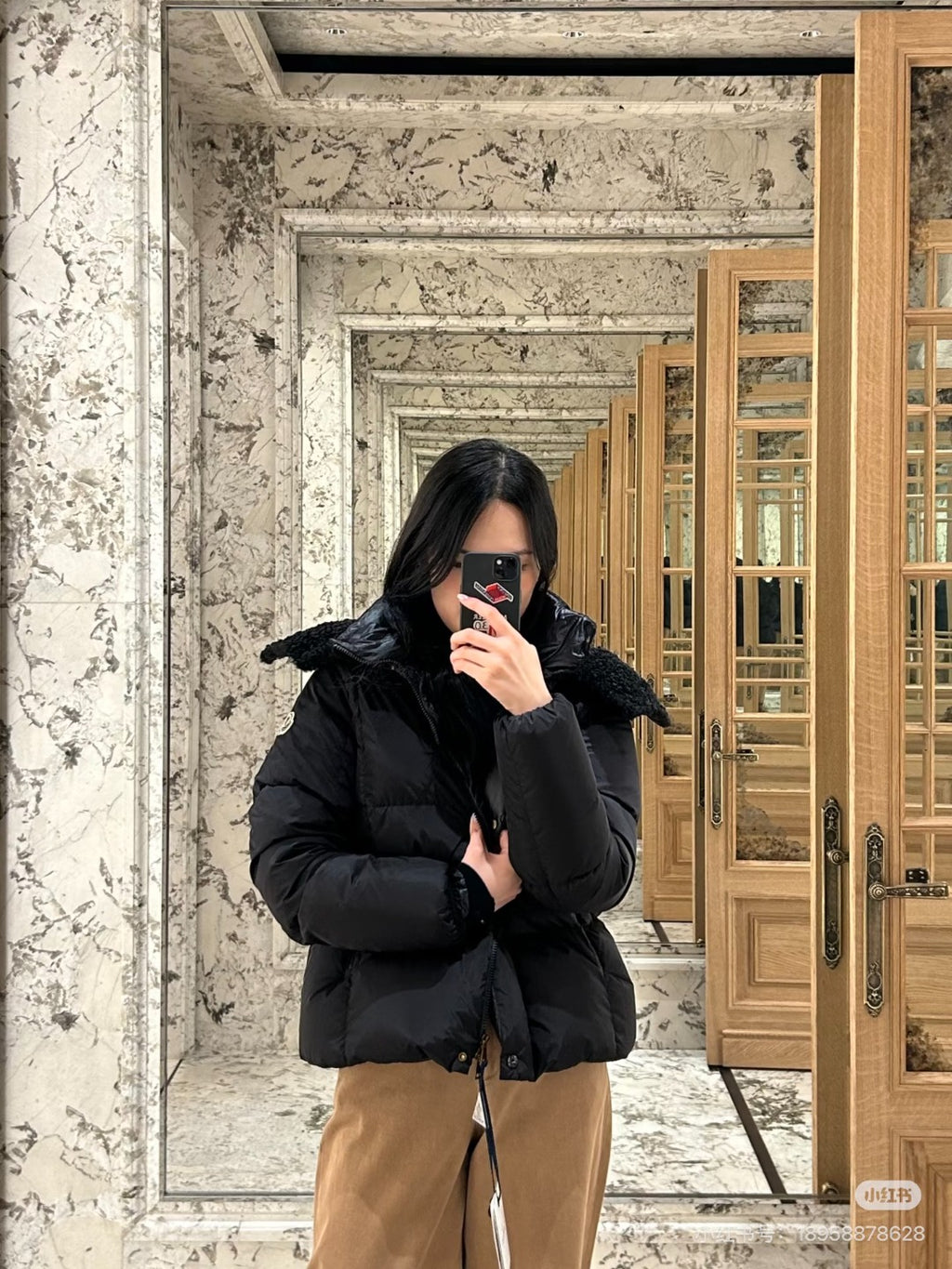 Long black puffer jacket with faux-fur hood, front zipper and mid-length hem