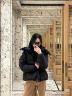 Long black puffer jacket with faux-fur hood, front zipper and mid-length hem