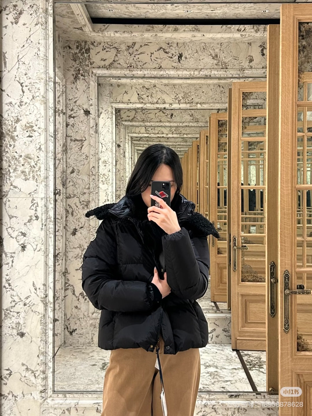 Long black puffer jacket with faux-fur hood, front zipper and mid-length hem