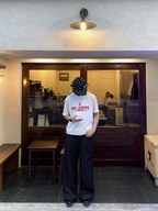 White logo T-shirt with red print, worn with dark pinstripe pants