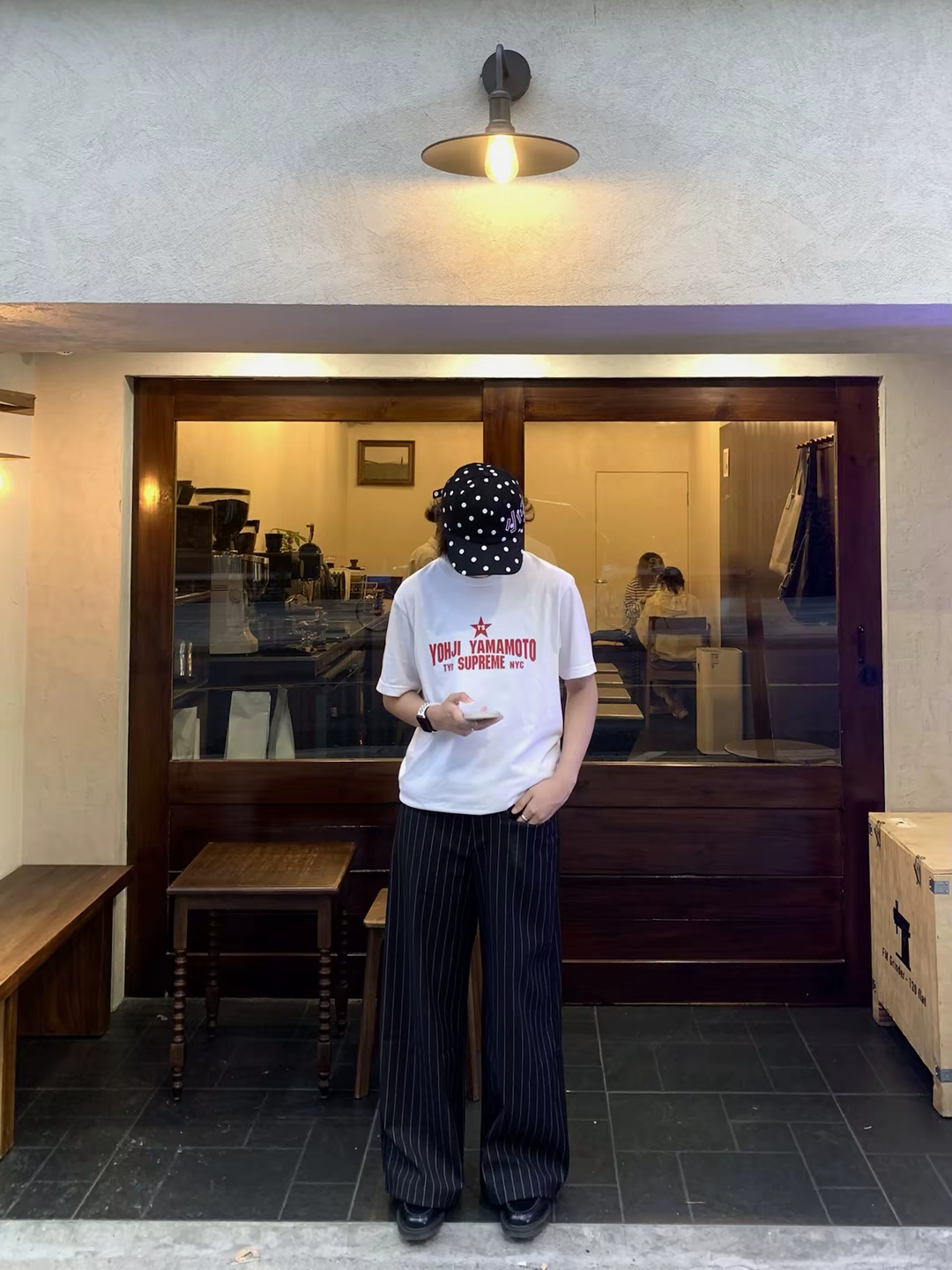 White logo T-shirt with red print, worn with dark pinstripe pants