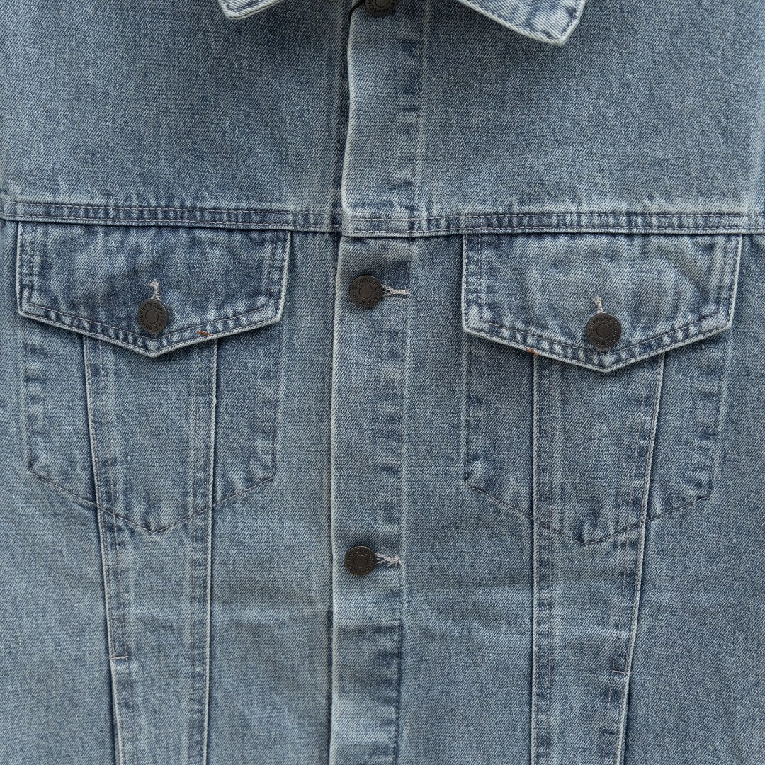 Front center close-up of long denim jacket with two chest flap pockets and buttons
