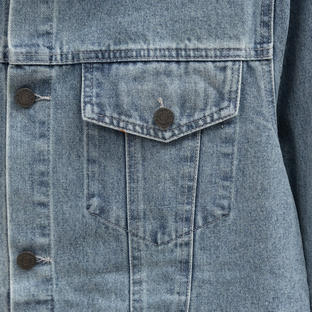 Denim jacket chest pocket close-up with buttoned flap and vertical seam stitching