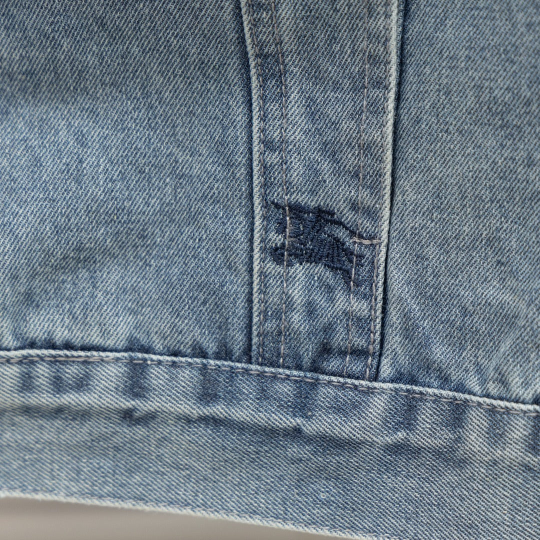 Denim jacket side panel close-up with frayed patch and contrast stitching at seam