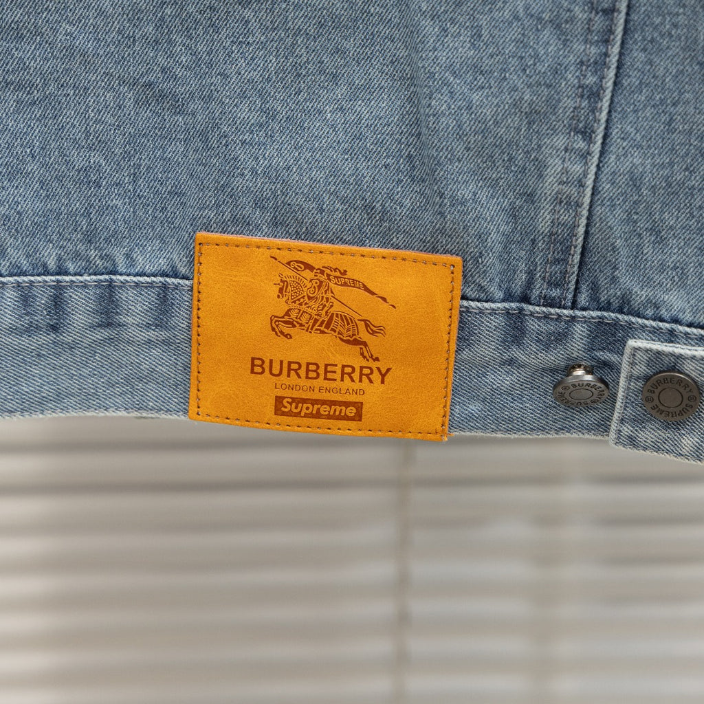 Light blue denim jacket with tan leather logo patch labeled Burberry Supreme