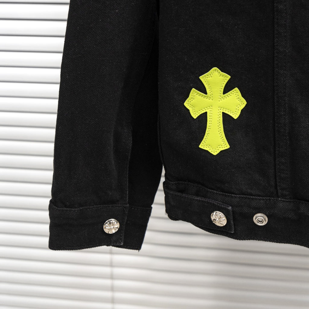 Black denim jacket sleeve with neon yellow cross patch and metal buttons