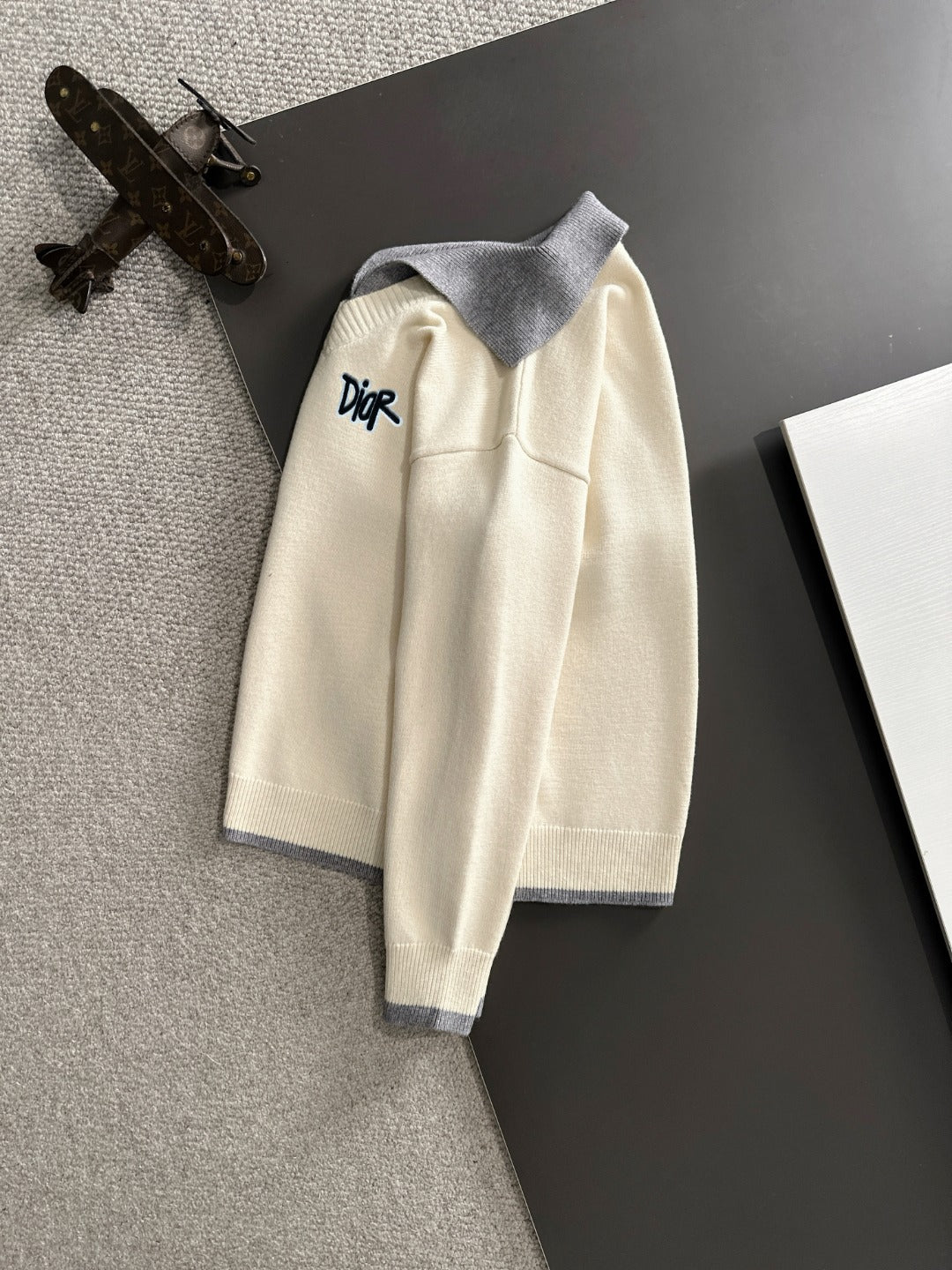 Cream long-sleeve sweater on hanger with light blue collar and Dior logo