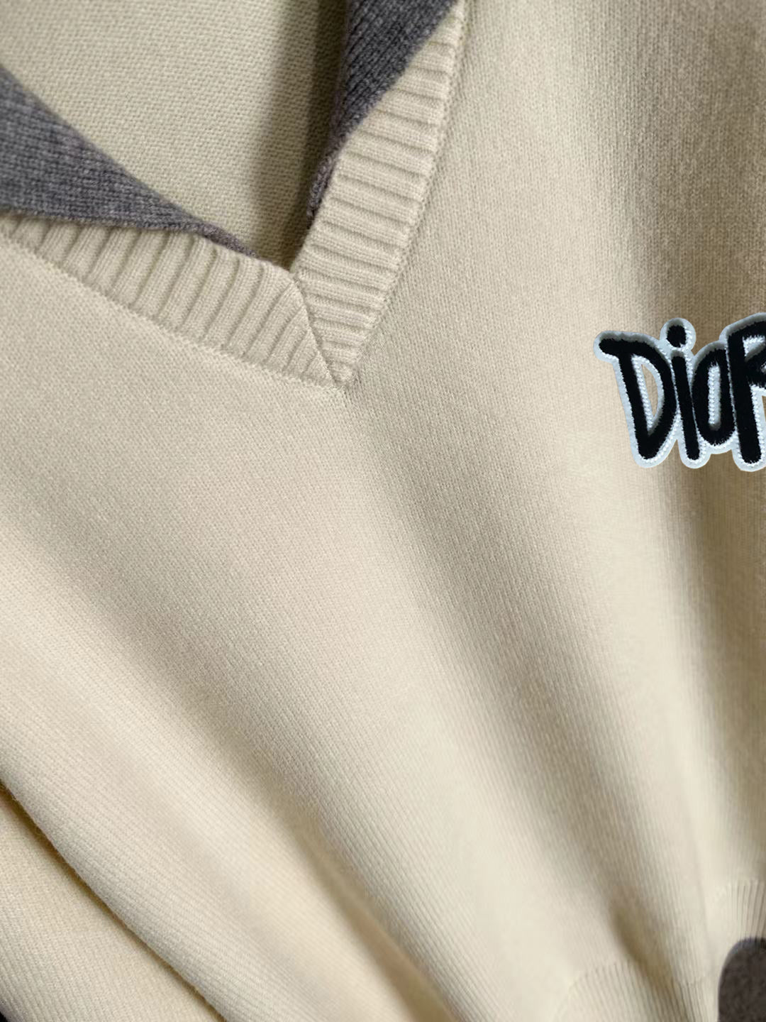 Cream sweater neckline with light blue ribbing and small Dior logo