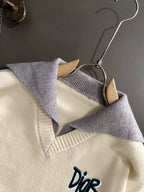Cream knit sweater with V-neck collar, light blue trim, and small Dior logo