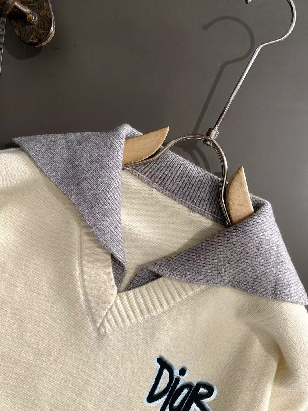 Cream knit sweater with V-neck collar, light blue trim, and small Dior logo
