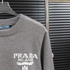 Prada heather gray sweater sleeve detail with PRADA Milano graphic on the front.