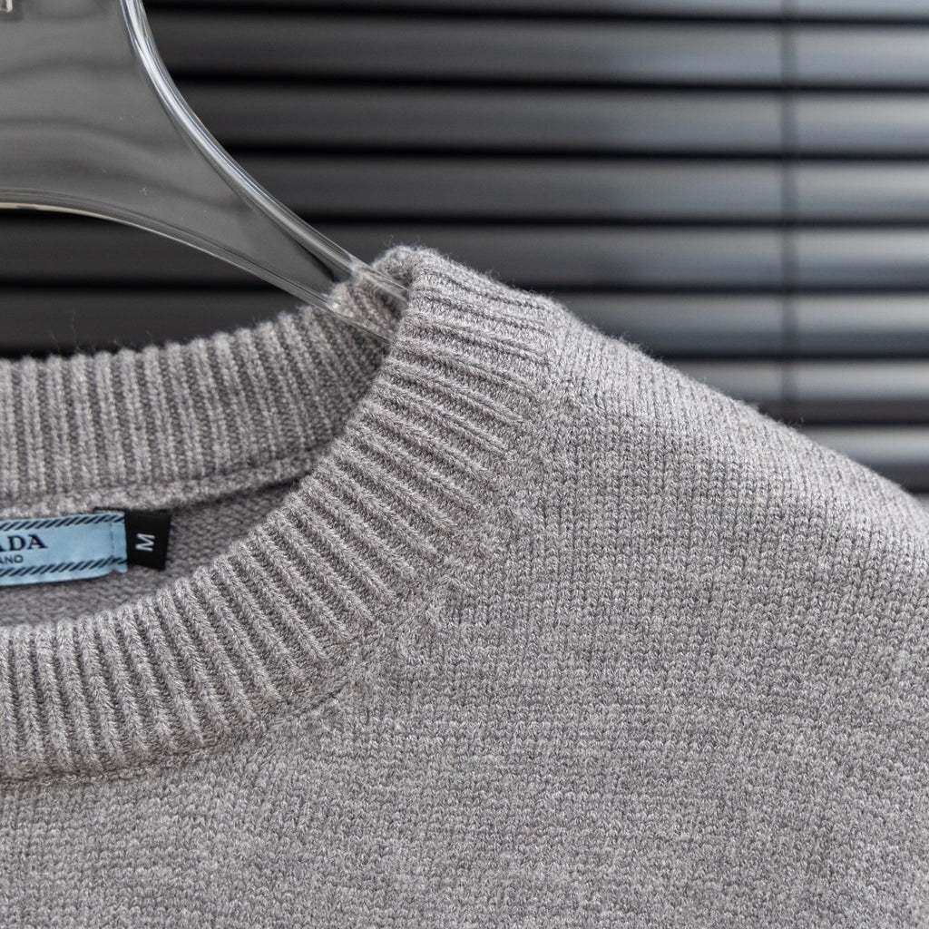 Prada heather gray knit sweater with ribbed crew neckline and fabric texture detail.