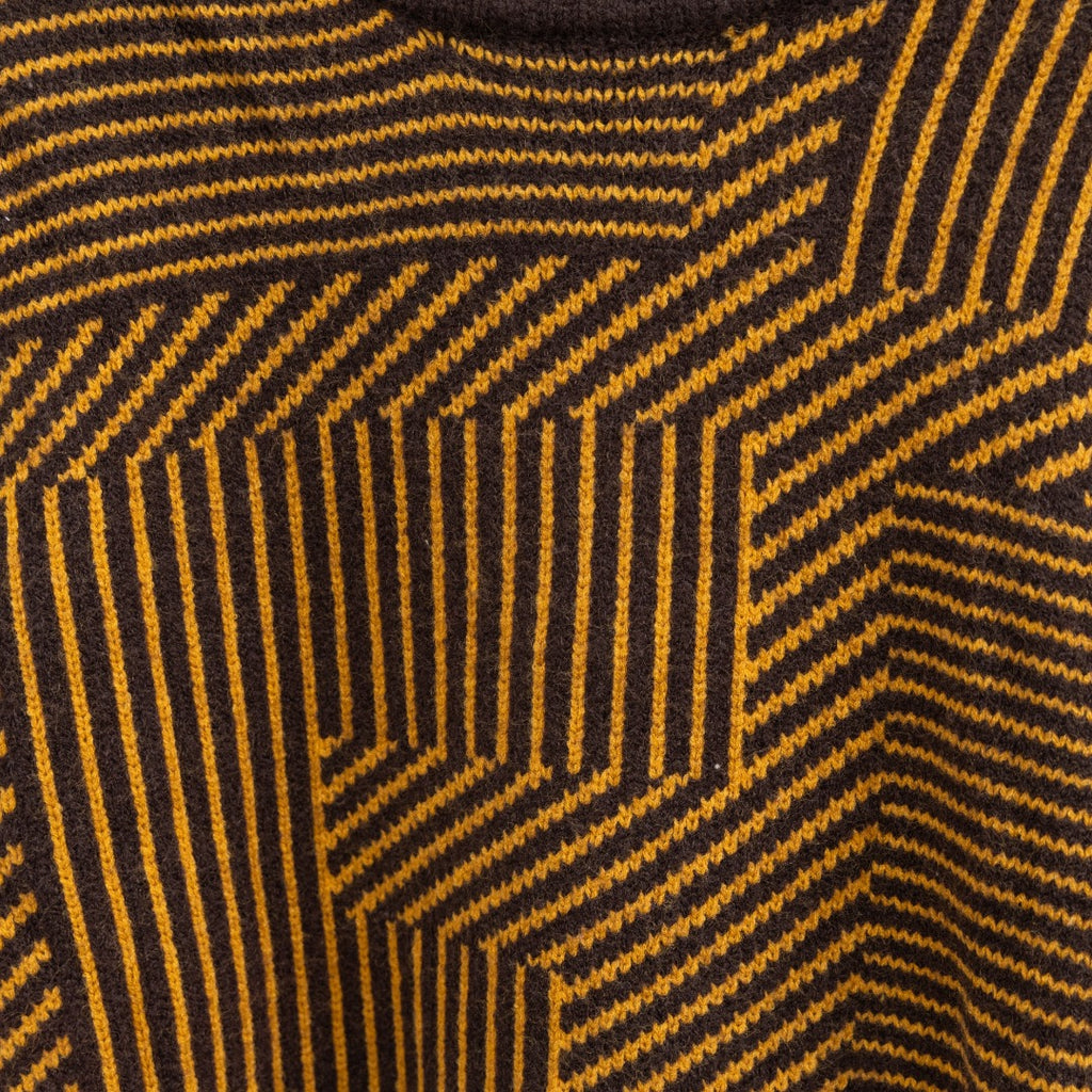 Long-sleeve sweater knit close-up with dark ground and yellow geometric stripes