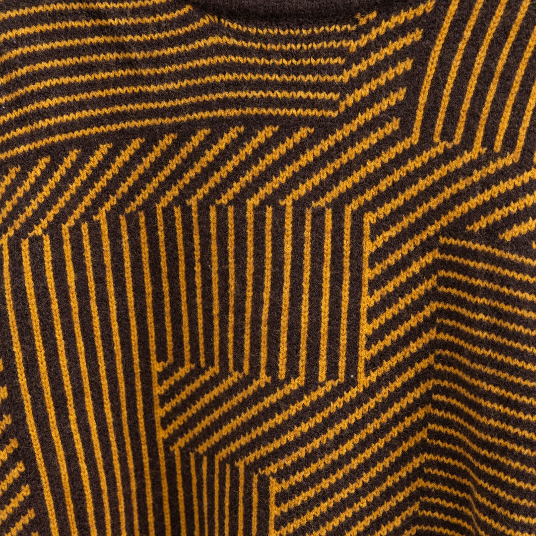 Long-sleeve sweater knit close-up with dark ground and yellow geometric stripes