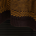 Long-sleeve sweater hem close-up with ribbed edge and brown/yellow striped knit
