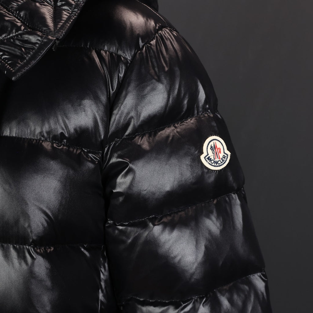 Long puffer coat chest with round Moncler logo patch and quilted black fabric