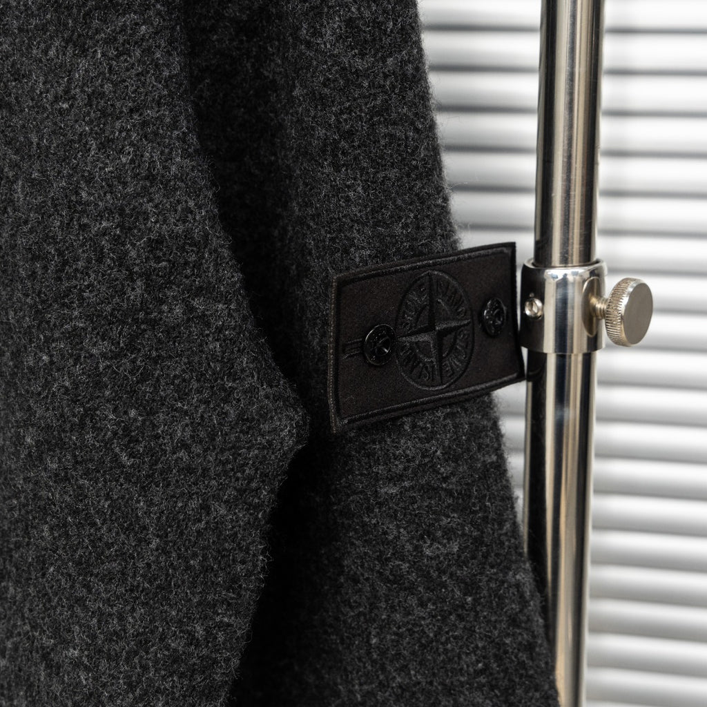 Stone Island sleeve patch detail with embossed logo on dark charcoal knit