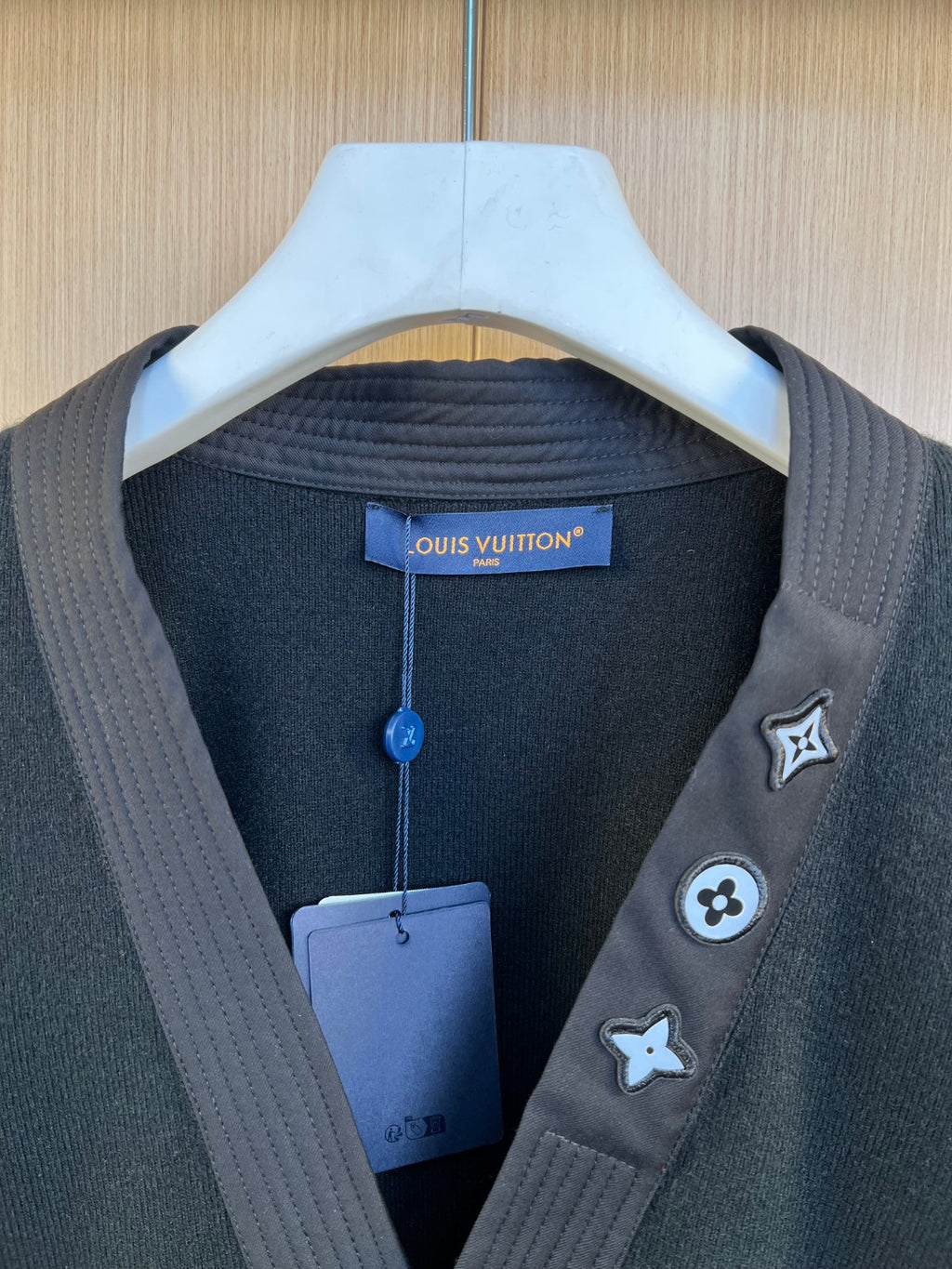 Long-sleeve V-neck sweater with chest patches and hanging tag, dark tone