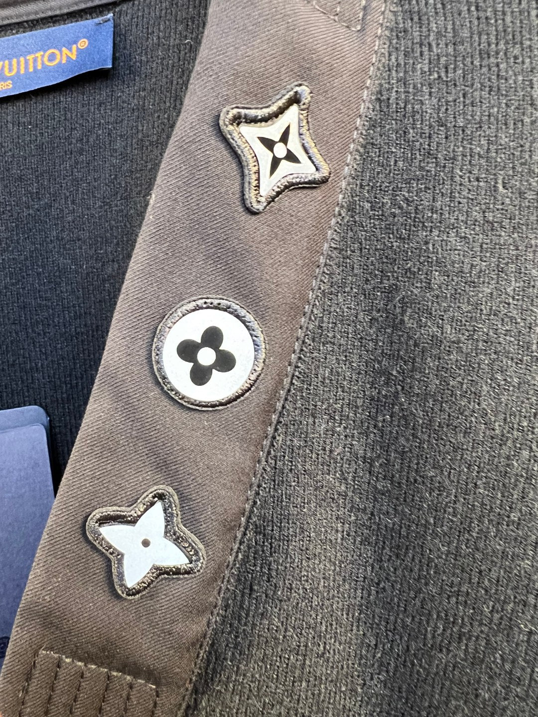 Close-up of sweater side trim with star and flower Louis Vuitton patches
