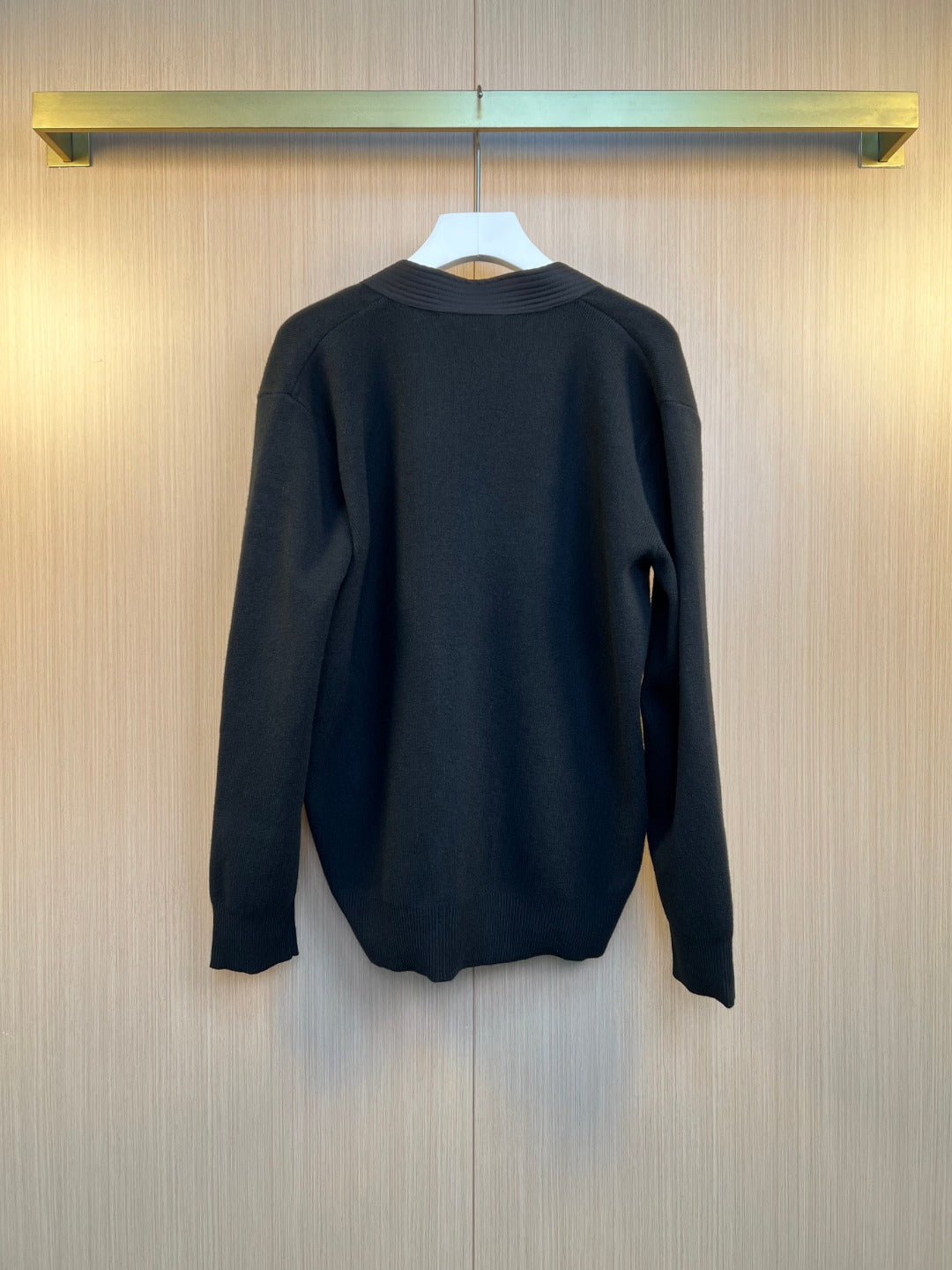 Back view of dark long-sleeve sweater on hanger