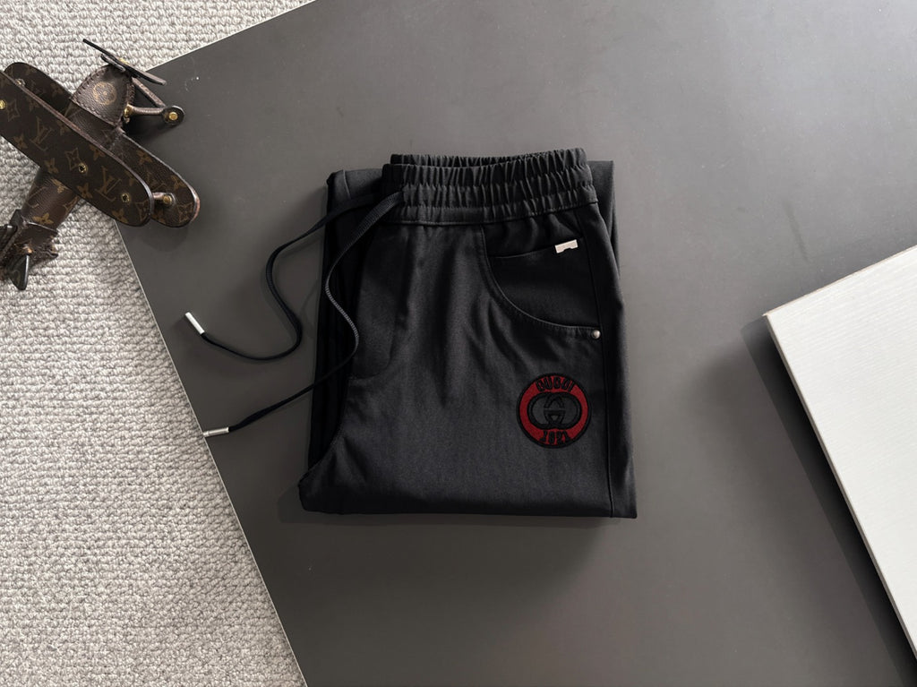 Black Gucci pants folded view with elastic waistband and red logo patch