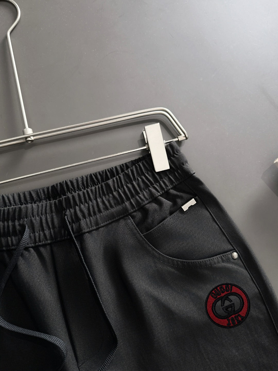 Black Gucci pants close-up of drawstring waist and logo patch on thigh