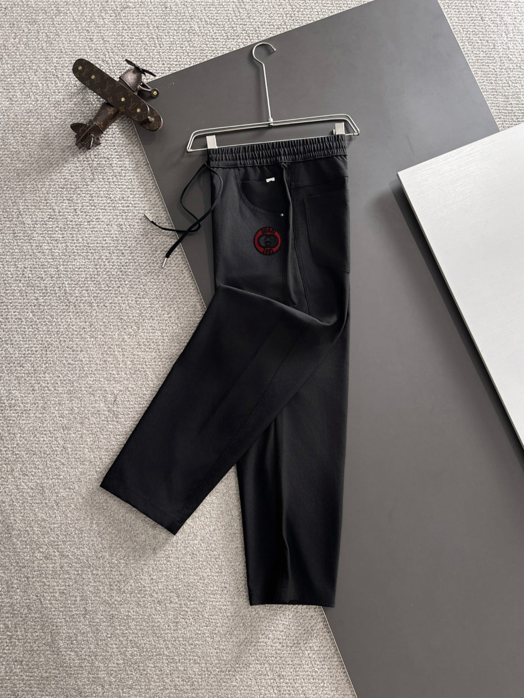 Black Gucci pants with elastic drawstring waist and red logo emblem