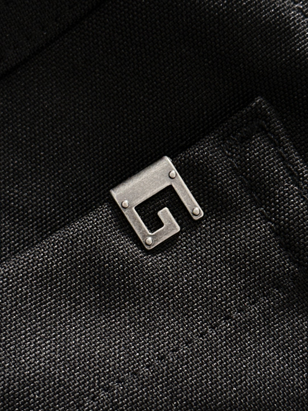Black Gucci pants fabric detail with metal buckle-like hardware