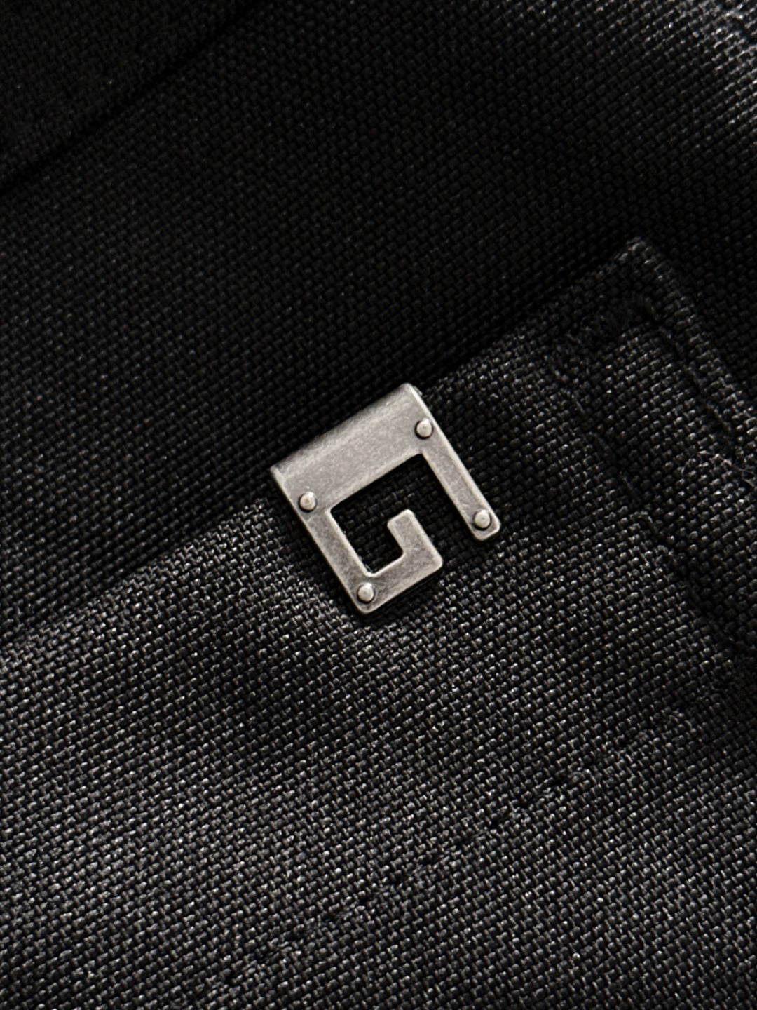 Black Gucci pants fabric detail with metal buckle-like hardware