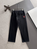 Black drawstring pants with elastic waistband and embroidered crest on thigh