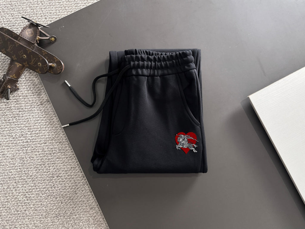 Black lounge pants with elastic waistband, drawstring cords, and crest