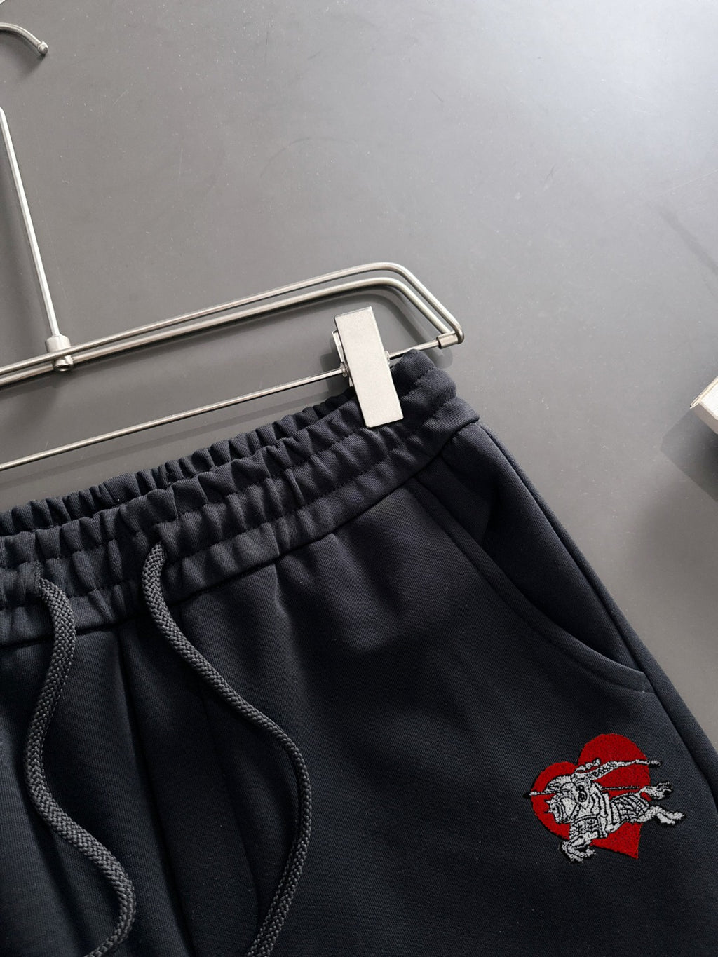 Black pants close-up with elastic waistband, drawstring, and crest patch