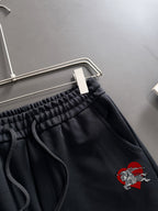 Black pants close-up with elastic waistband, drawstring, and crest patch