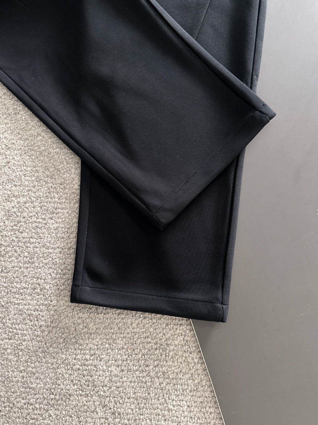 Black straight-leg pants with side seam and stitched fold