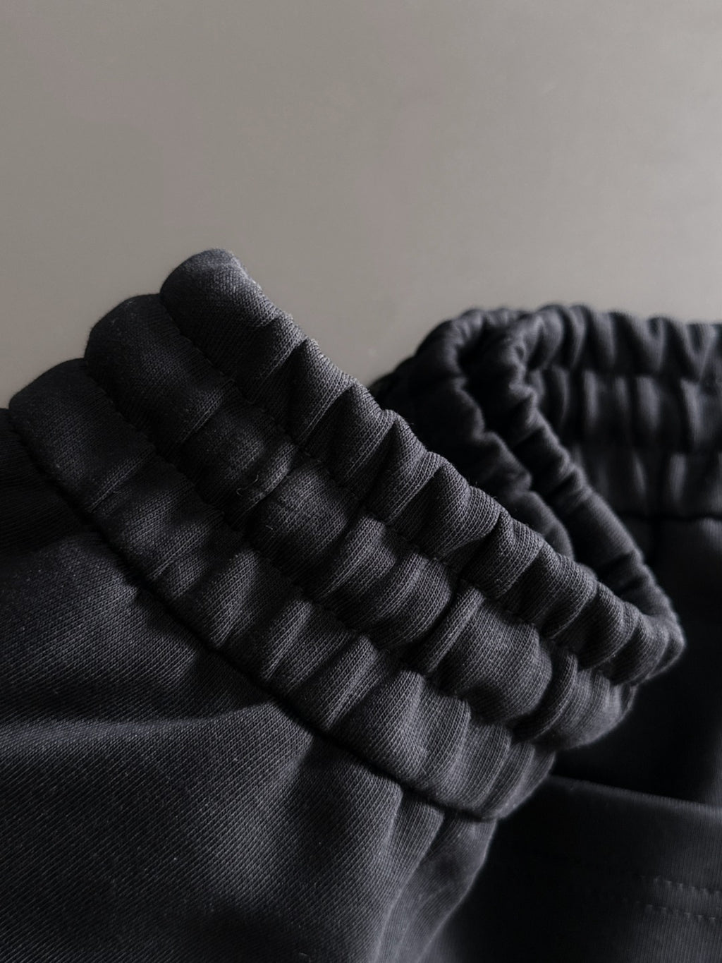 Black pants fabric close-up with ribbed elastic waistband detail