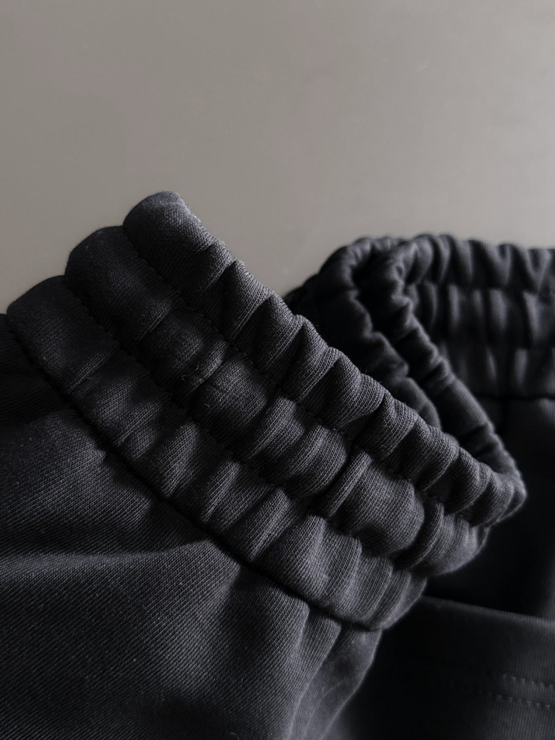 Black pants fabric close-up with ribbed elastic waistband detail