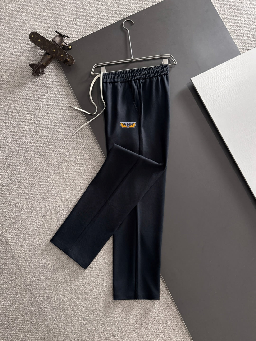 Navy straight pants on hanger with elastic waistband and FENDI logo patch