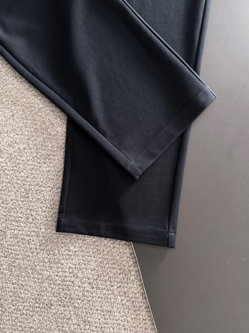 Navy straight-leg pants folded flat, smooth fabric with side crease