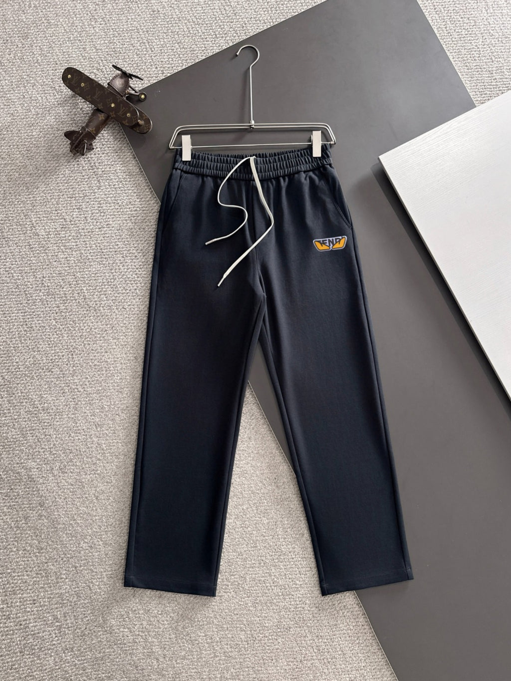 Navy drawstring pants with elastic waistband, front logo patch, cuffed straight legs