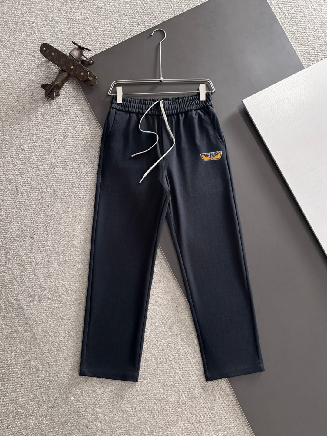 Navy drawstring pants with elastic waistband, front logo patch, cuffed straight legs