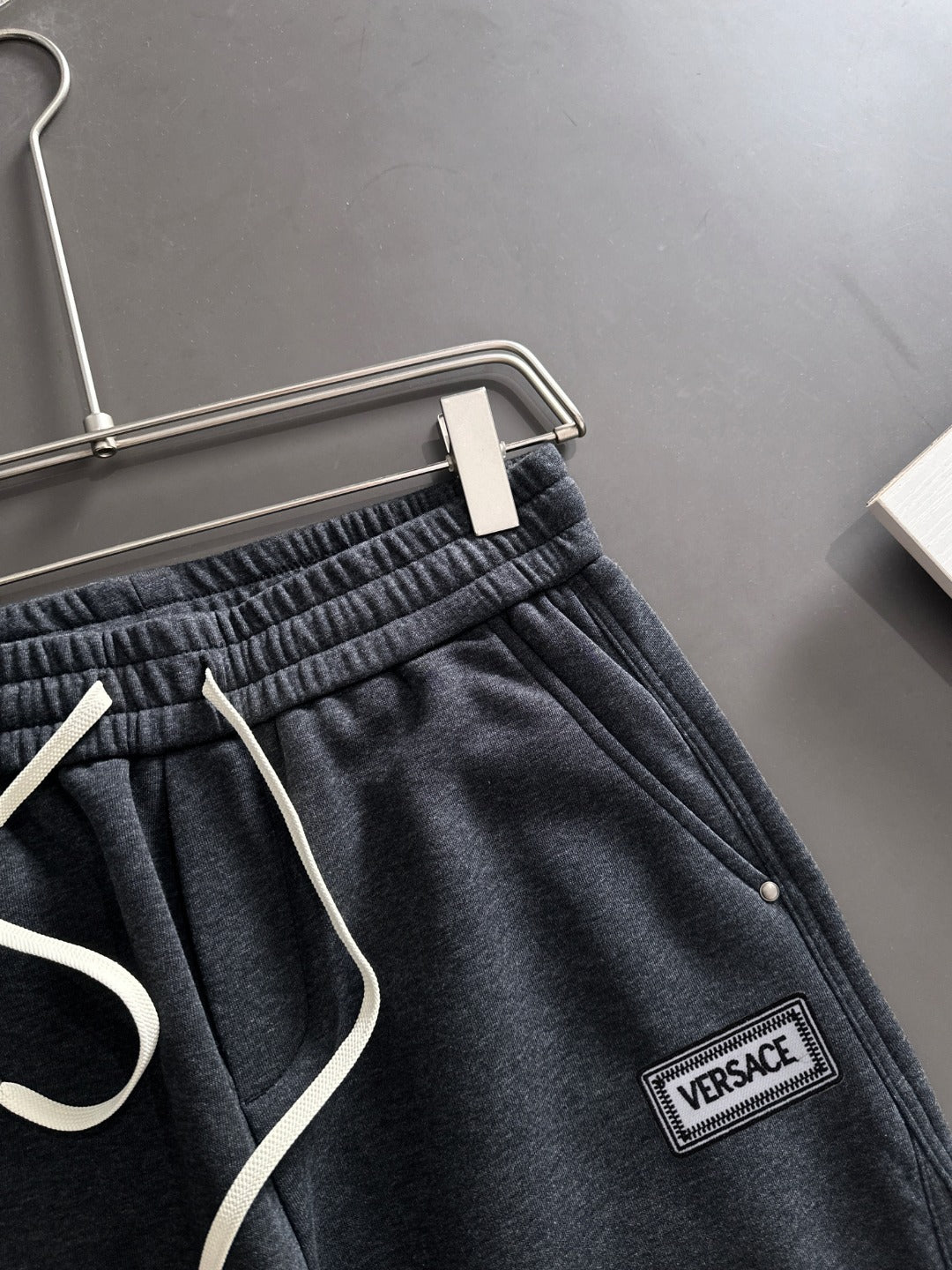 Dark jogger pants close-up of drawstring, elastic waistband, and Versace logo patch