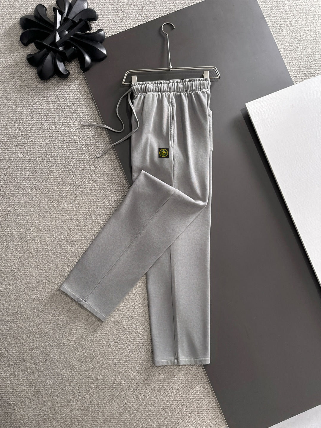 Stone Island light gray sweatpants on hanger, drawstring ties and relaxed straight legs