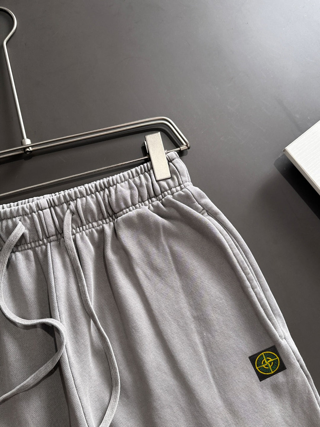 Stone Island light gray sweatpants with front pocket, elastic waistband, and drawstring