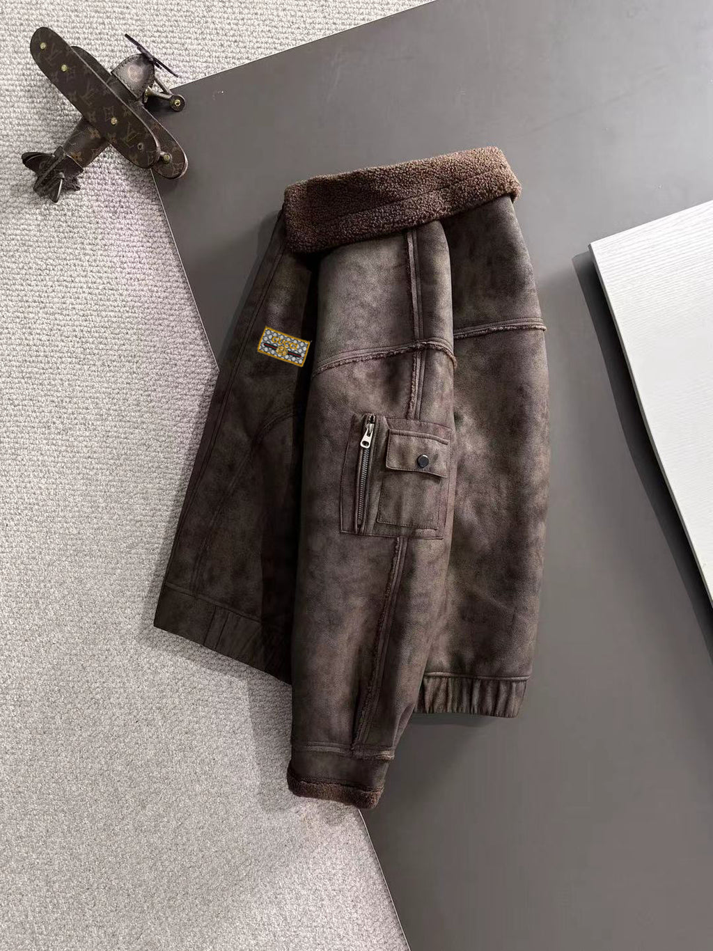 Brown shearling-lined jacket with front logo patch and buttoned pocket placket