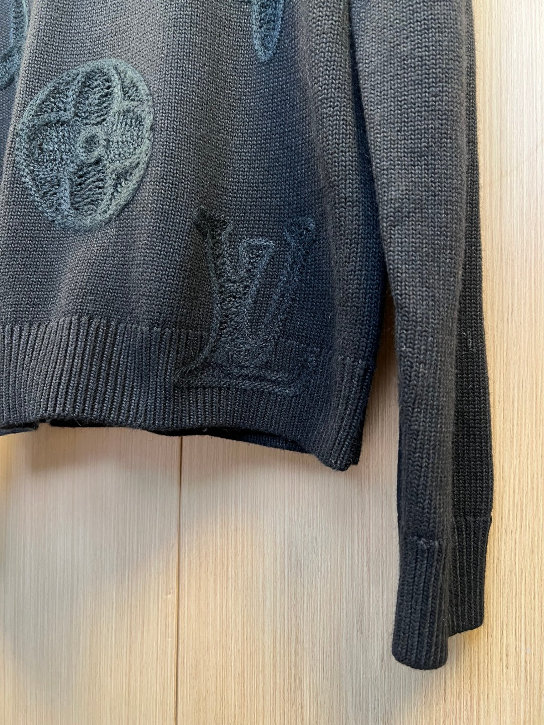 Dark knit sweater sleeve with ribbed cuff and embroidered detail