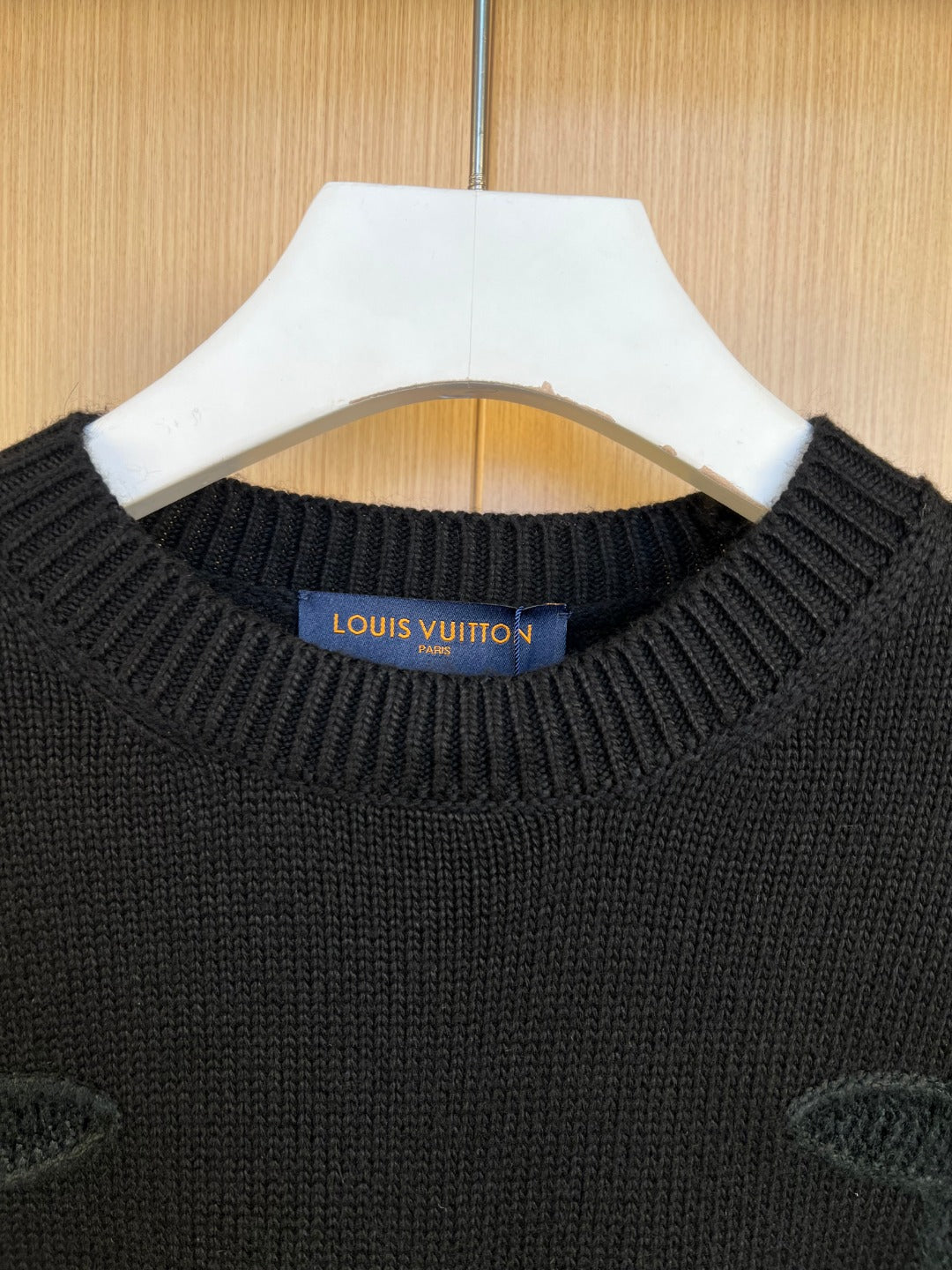 Dark knit sweater neckline with Louis Vuitton logo patch