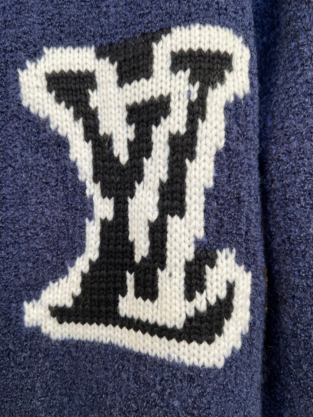 White LV-style logo intarsia on a navy knit cardigan