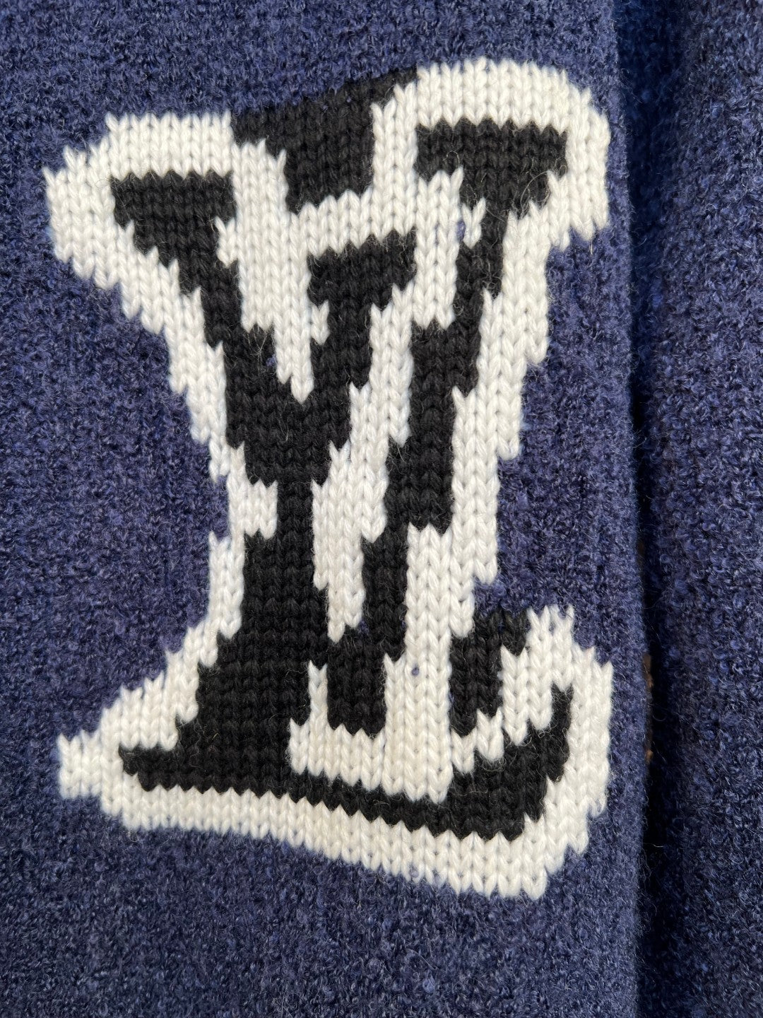 White LV-style logo intarsia on a navy knit cardigan